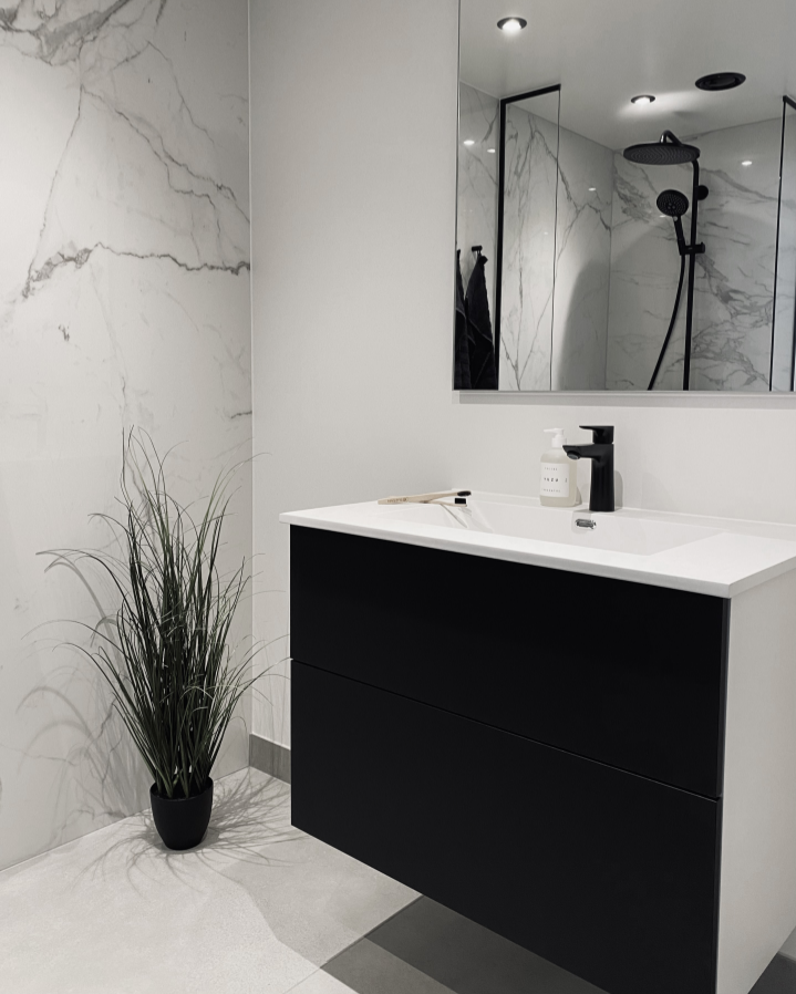 Prefab bathroom from Green Box with black interior and large format tiles (slabs) with marble effect.