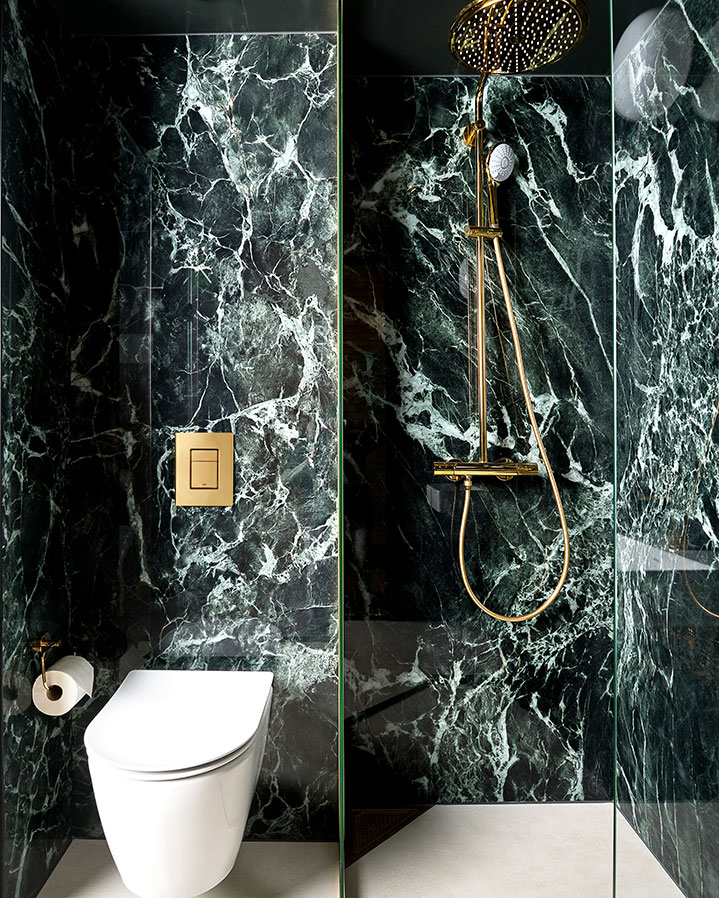 Prefab bathroom from Green Box with green, marble-patterned large-format tiles (slabs) on the walls in hotel building.