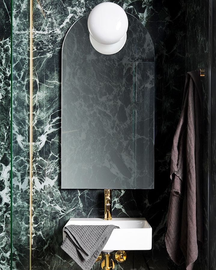 Prefab bathroom from Green Box with green, marble-patterned large-format tiles (slabs) on the walls in hotel building.